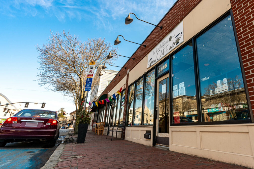 The Roasted Granola Cafe storefront on a sunny winter day with rainbow flag bunting, Arlington MA.