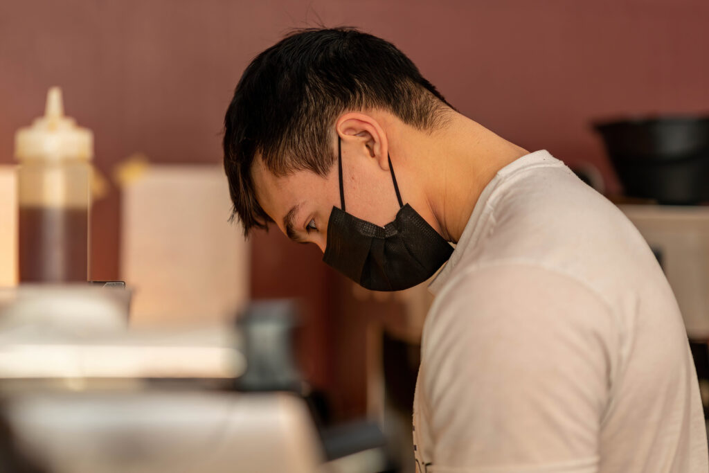Barista in profile working at the espresso machine at The Roasted Granola.