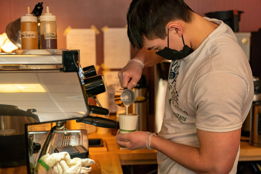 Barista pouring espresso into a cup at the machine at The Roasted Granola.