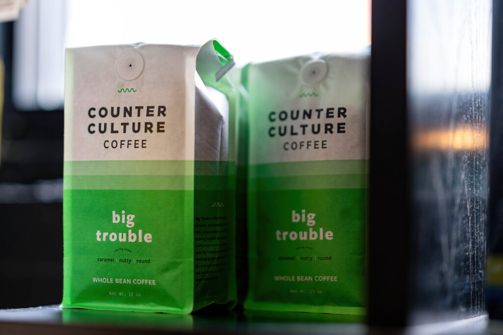 Two bags of Counter Culture Big Trouble whole bean coffee in the window at The Roasted Granola.