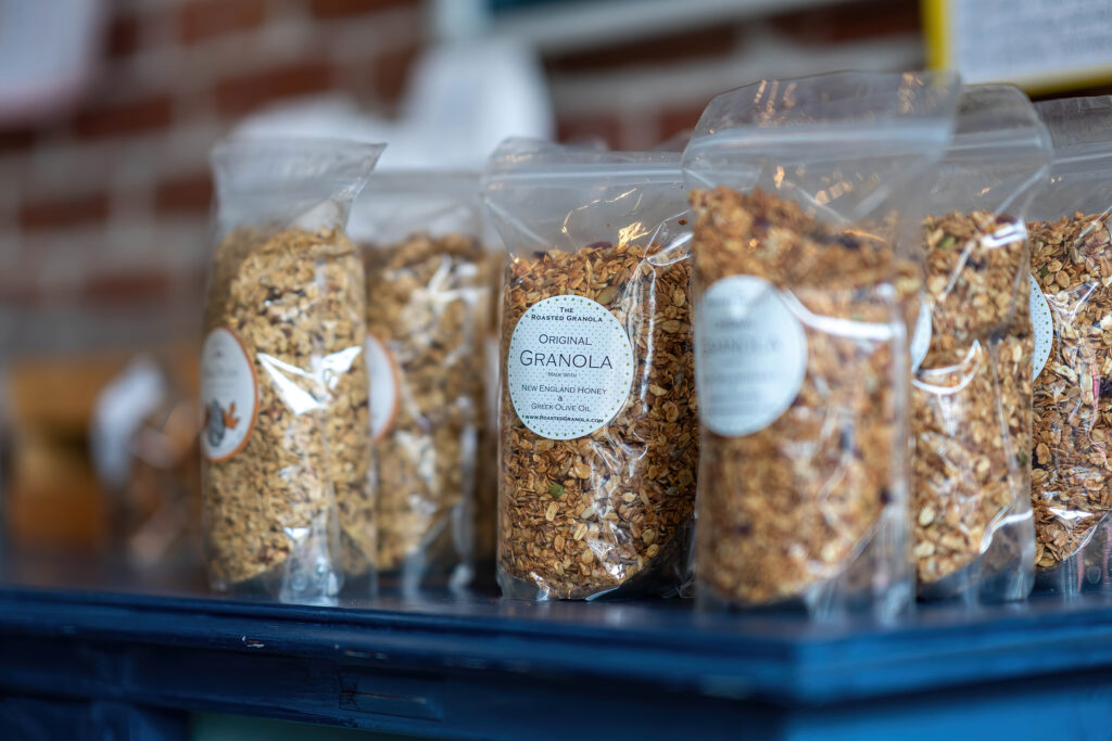 Clear bags of Original Granola from The Roasted Granola lined up on a blue counter.
