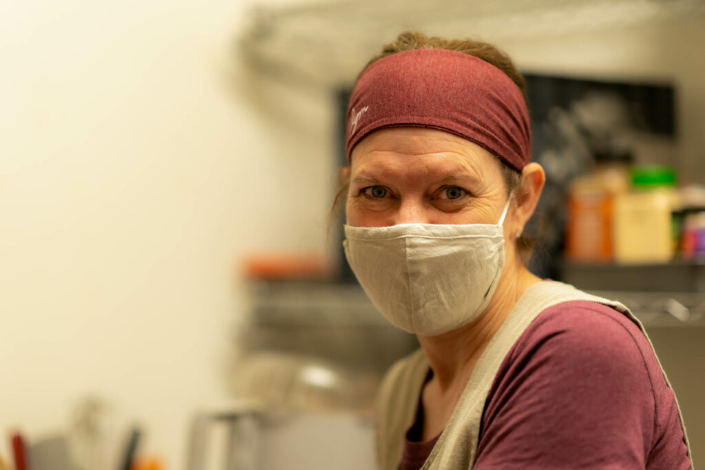 Team member in a maroon headband and cloth mask in The Roasted Granola kitchen.
