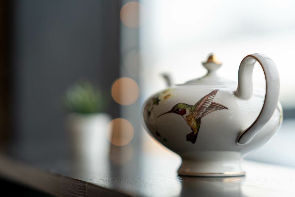 Porcelain teapot painted with a hummingbird on the windowsill at The Roasted Granola.