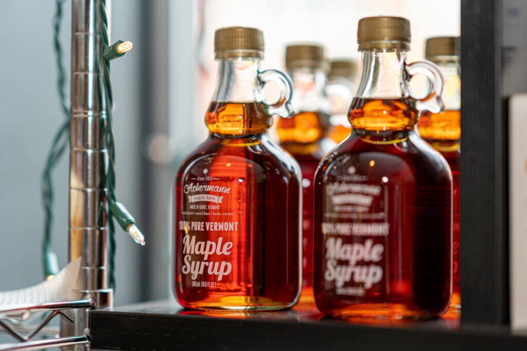 Glass jugs of pure Vermont maple syrup on a shelf at The Roasted Granola.